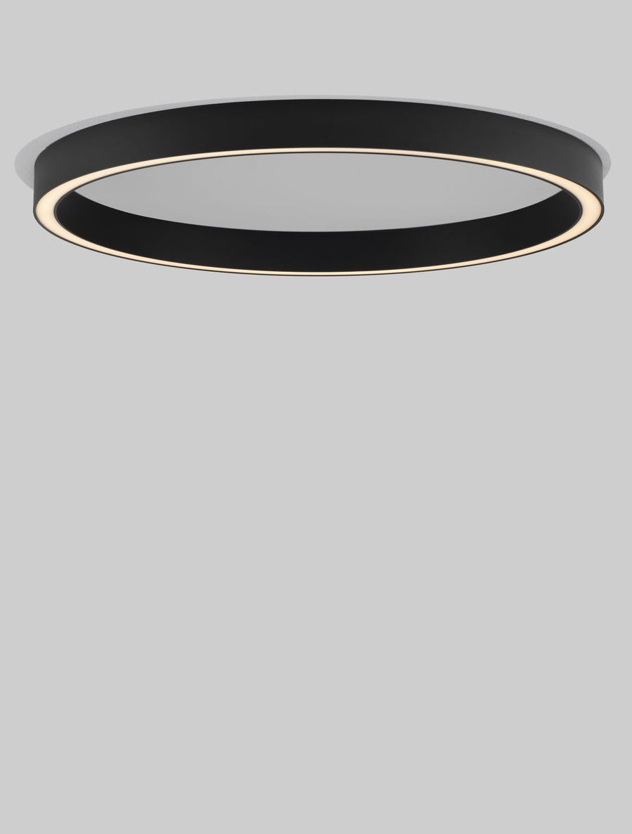 Détail du luminaire allumé, anneau noir et lumière chaude.