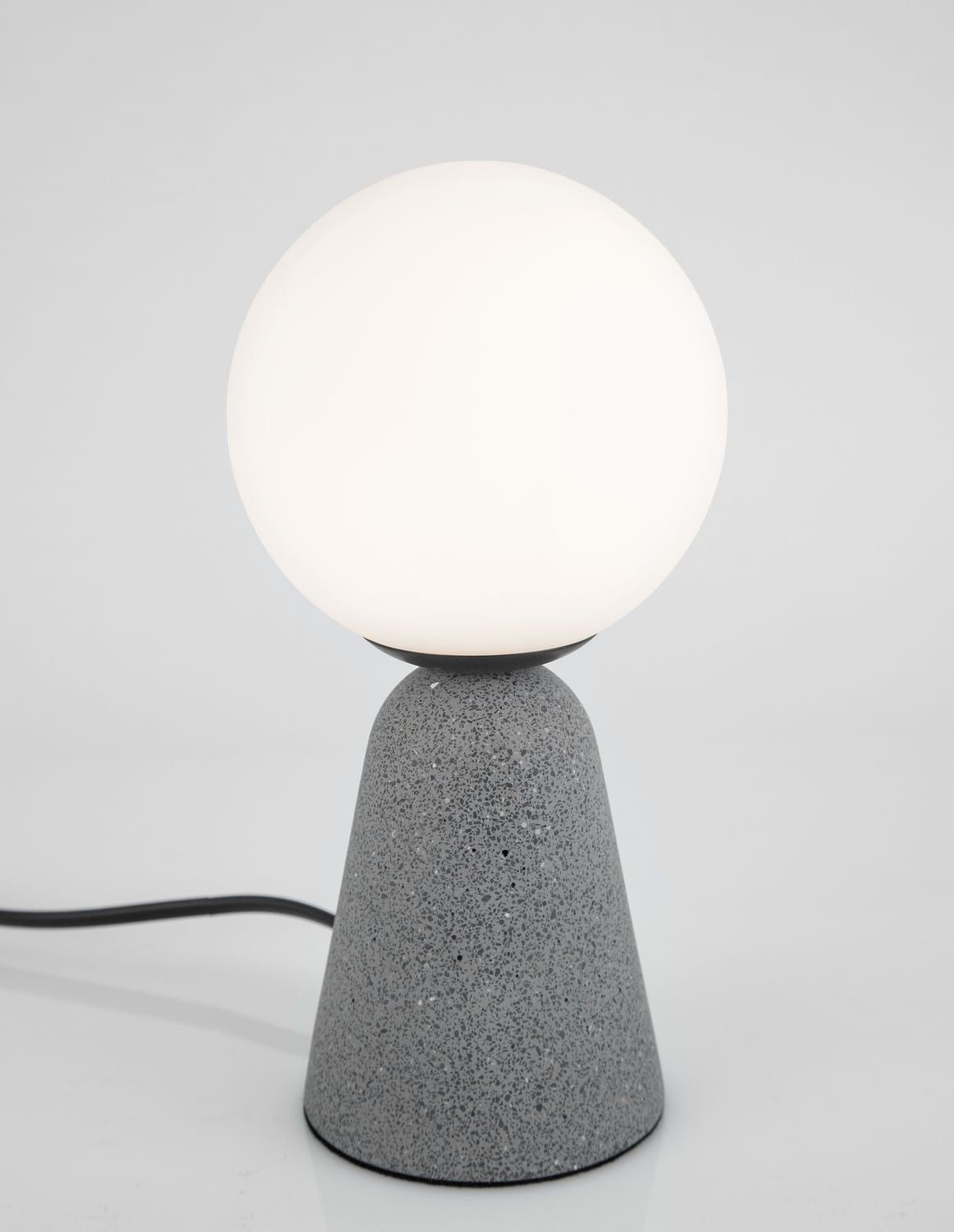 Vue de trois quarts de la lampe allumée, câble noir posé au sol