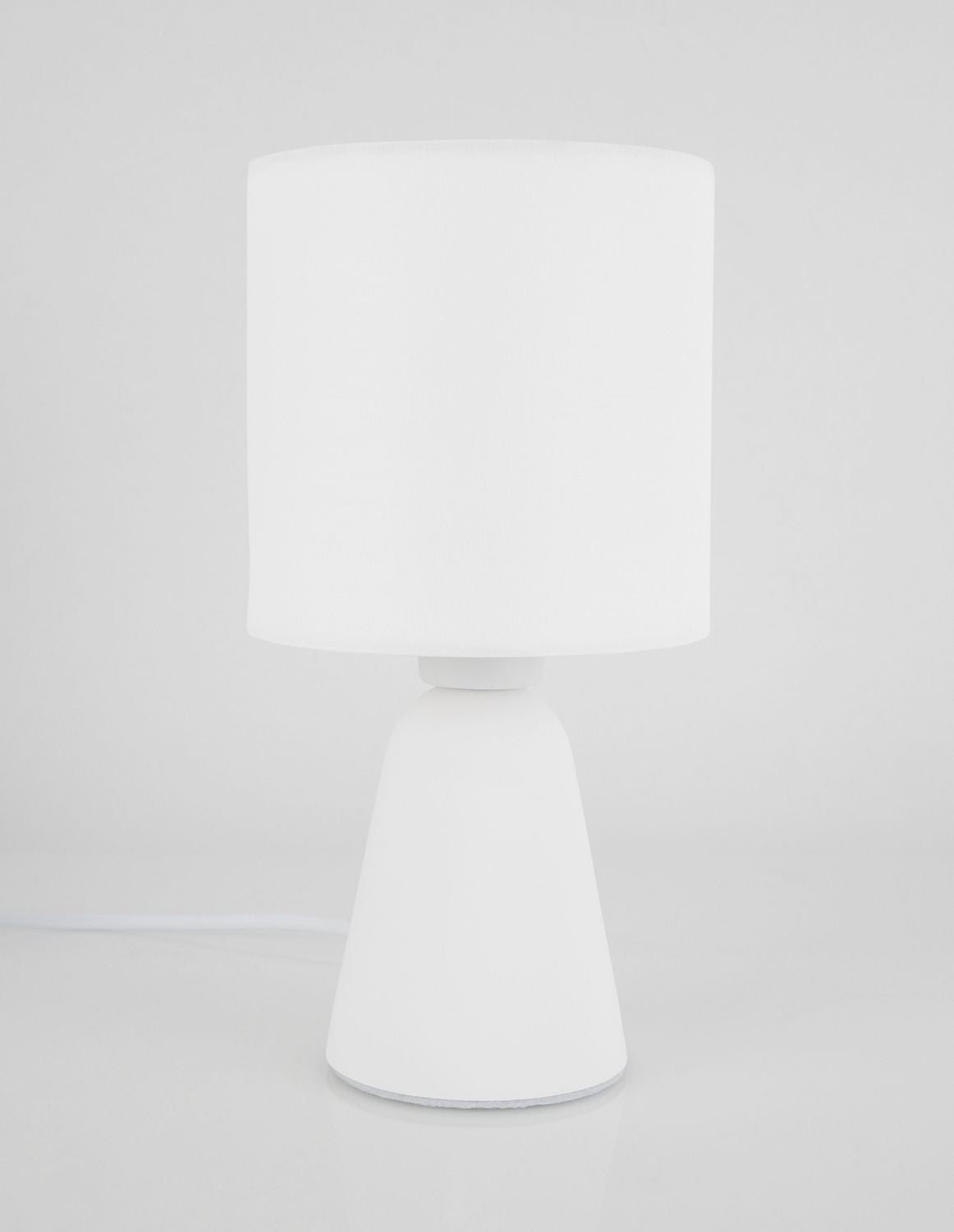 Vue de face du luminaire, socle conique posé sur une surface claire