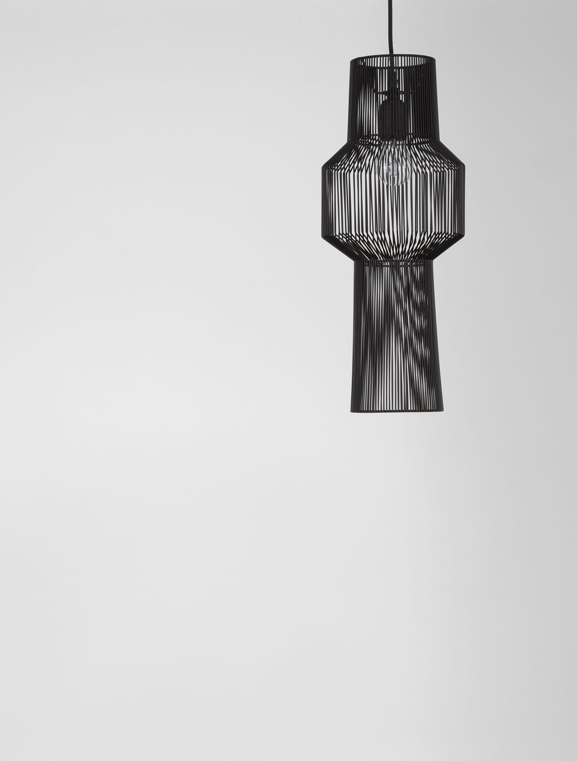 Gros plan du luminaire noir sur fond gris clair, silhouette détaillée