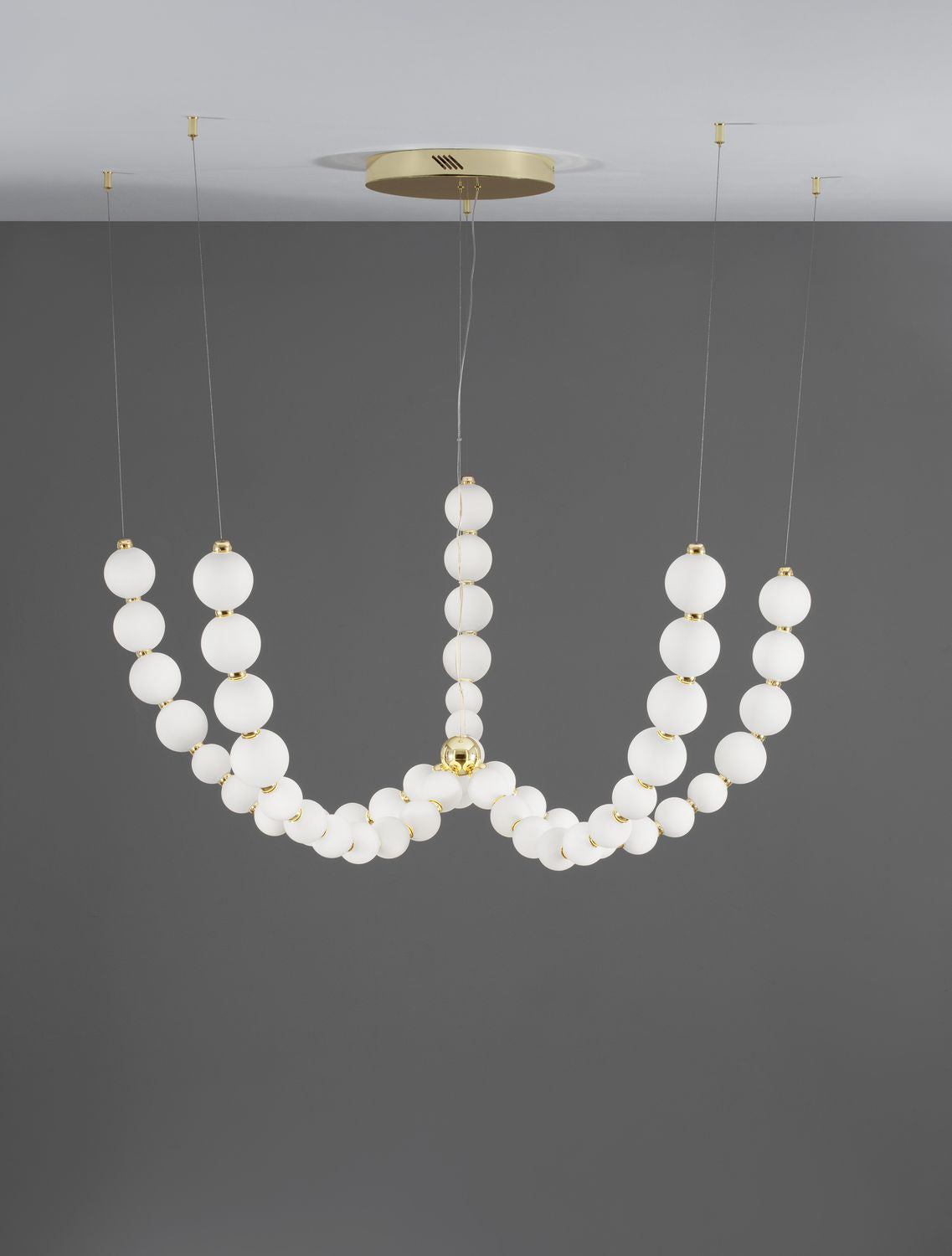 Luminaire suspendu vu de face sur fond gris, rosace et finitions dorées