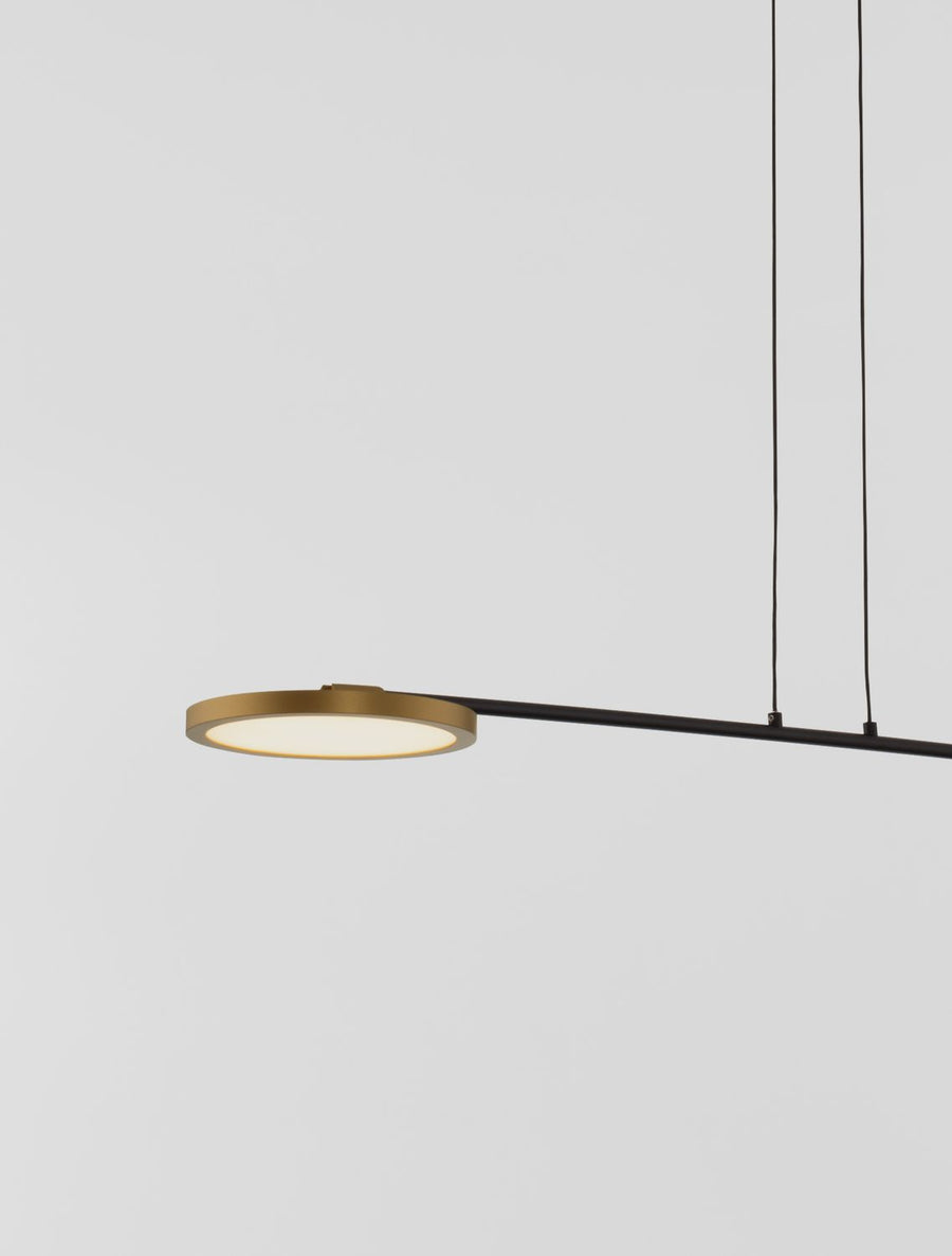 Détail d'une tête lumineuse ronde à cerclage laiton sur barre noire