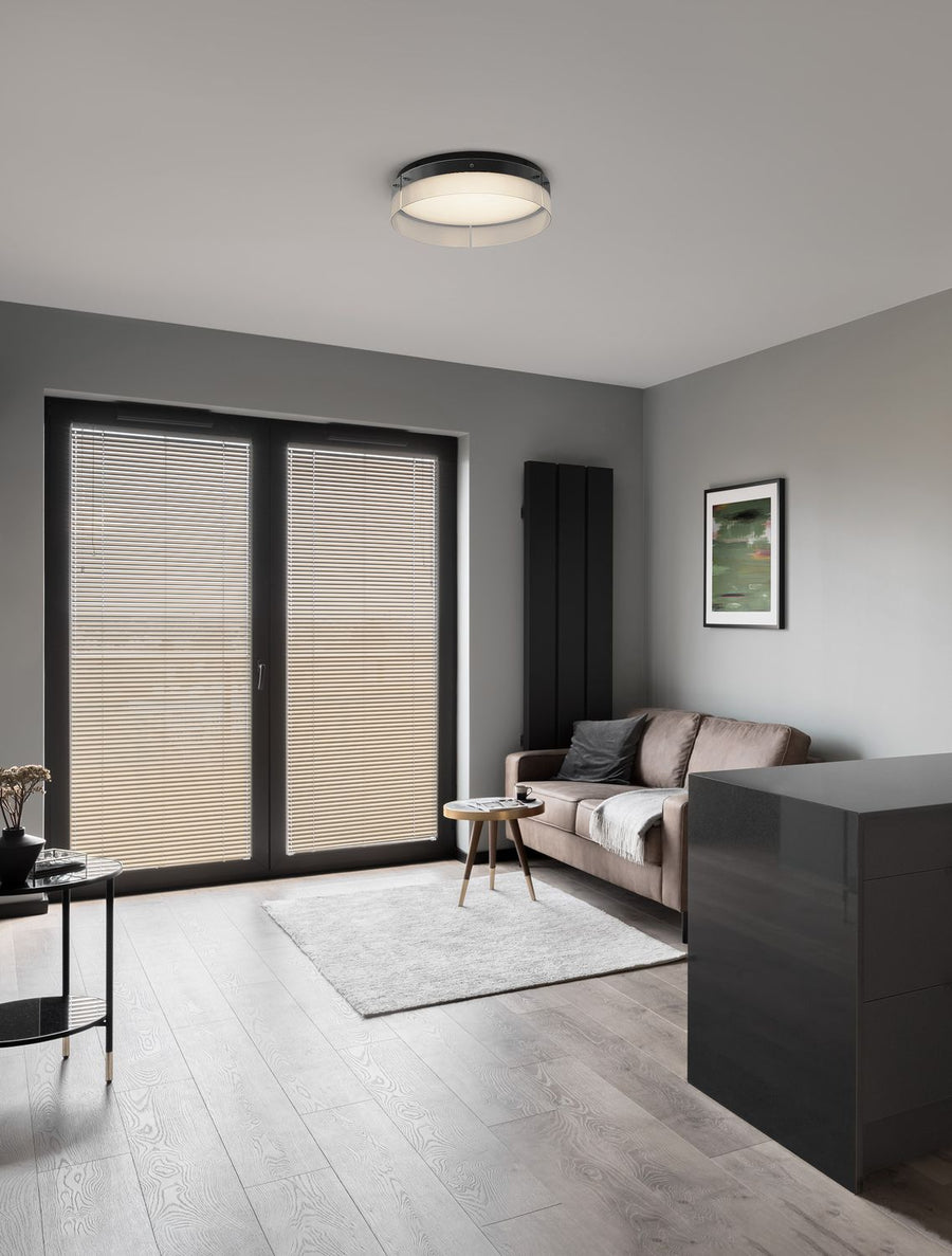 Plafonnier rond noir et verre strié installé au plafond d'un salon gris