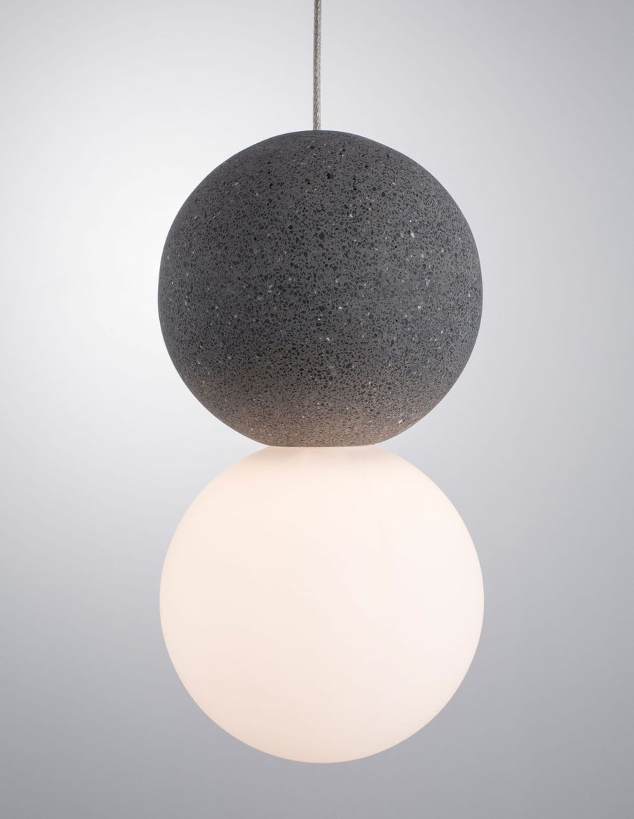 Gros plan sur la sphère texturée gris anthracite posée sur le globe blanc