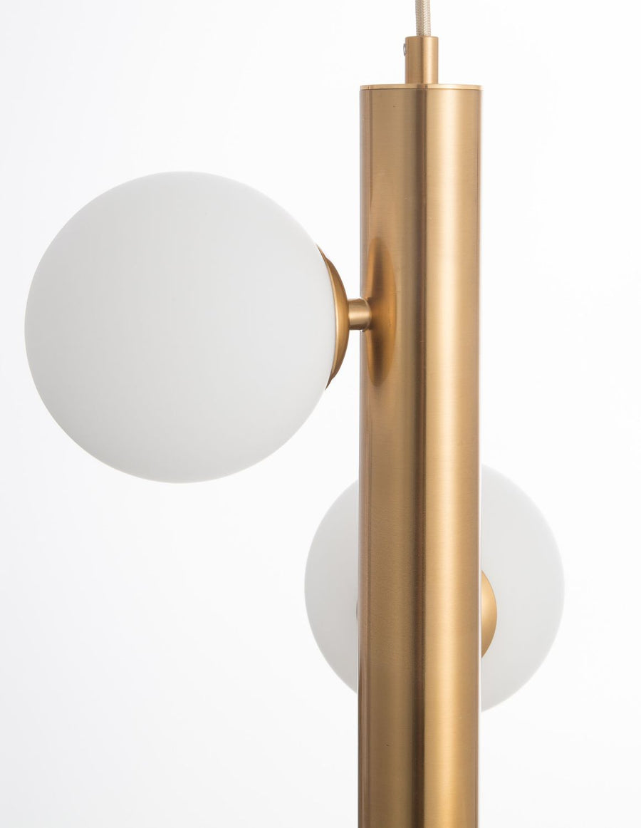 Gros plan sur un globe en verre blanc fixé au tube doré vertical.