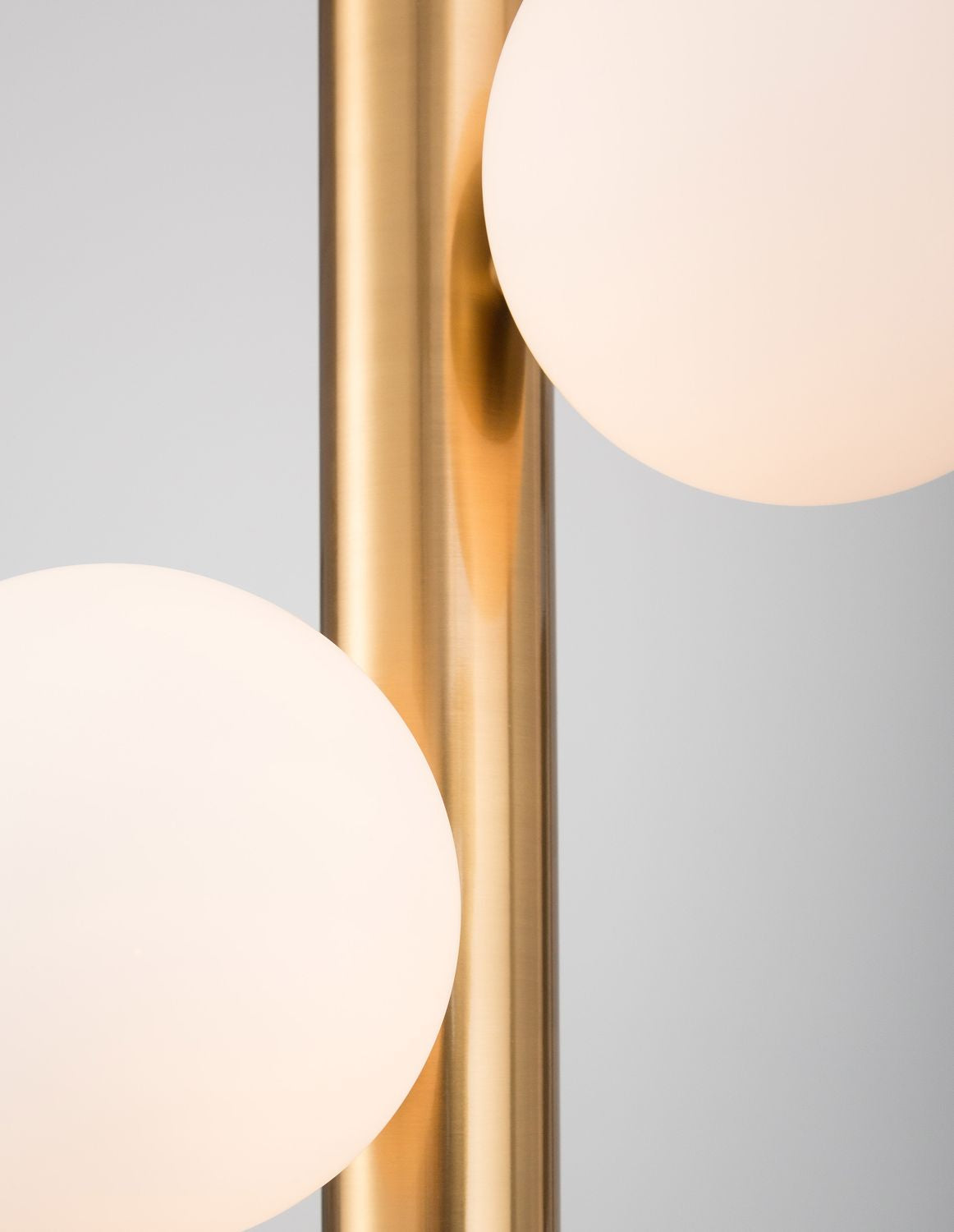 Détail rapproché du tube doré reflétant la lumière entre deux sphères blanches