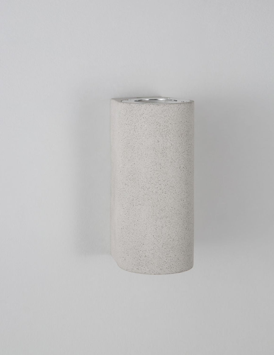 Vue de trois quarts sur fond gris, volume cylindrique et texture bétonné clair