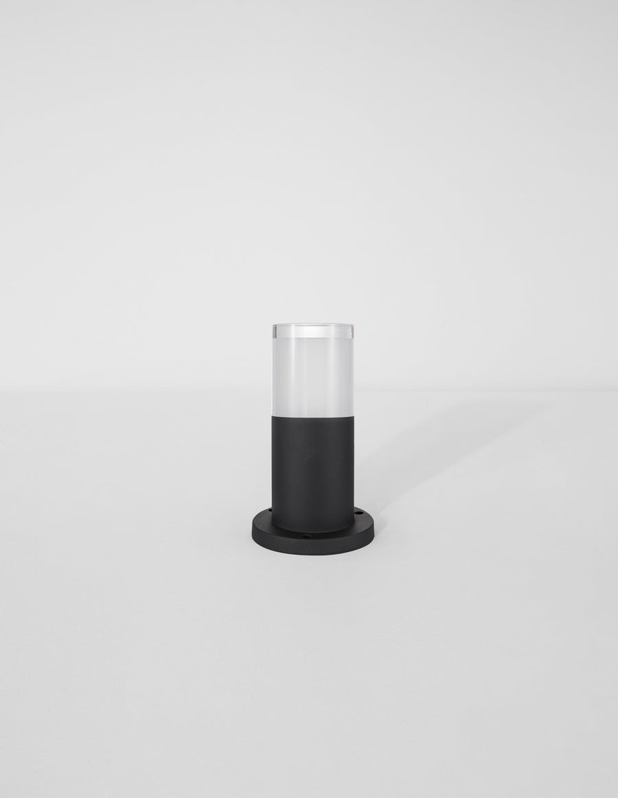 Luminaire cylindrique noir et translucide présenté seul sur fond gris clair.