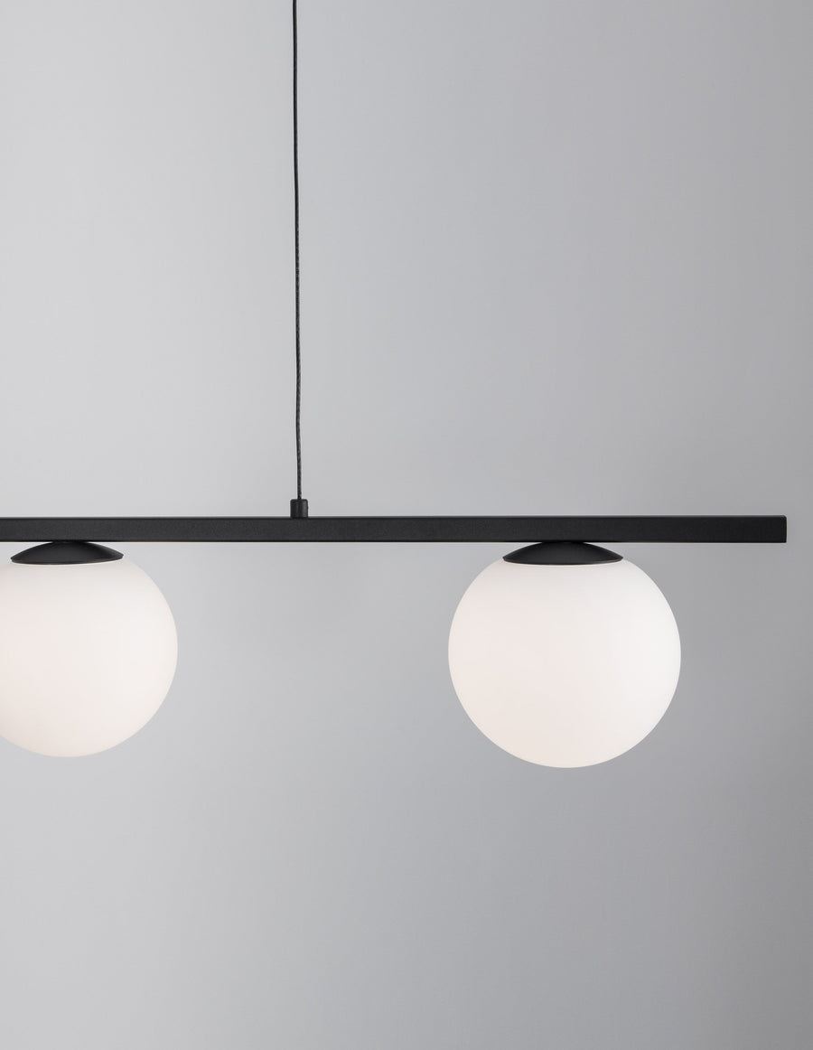 Détail rapproché de deux globes en verre dépoli et du câble de suspension