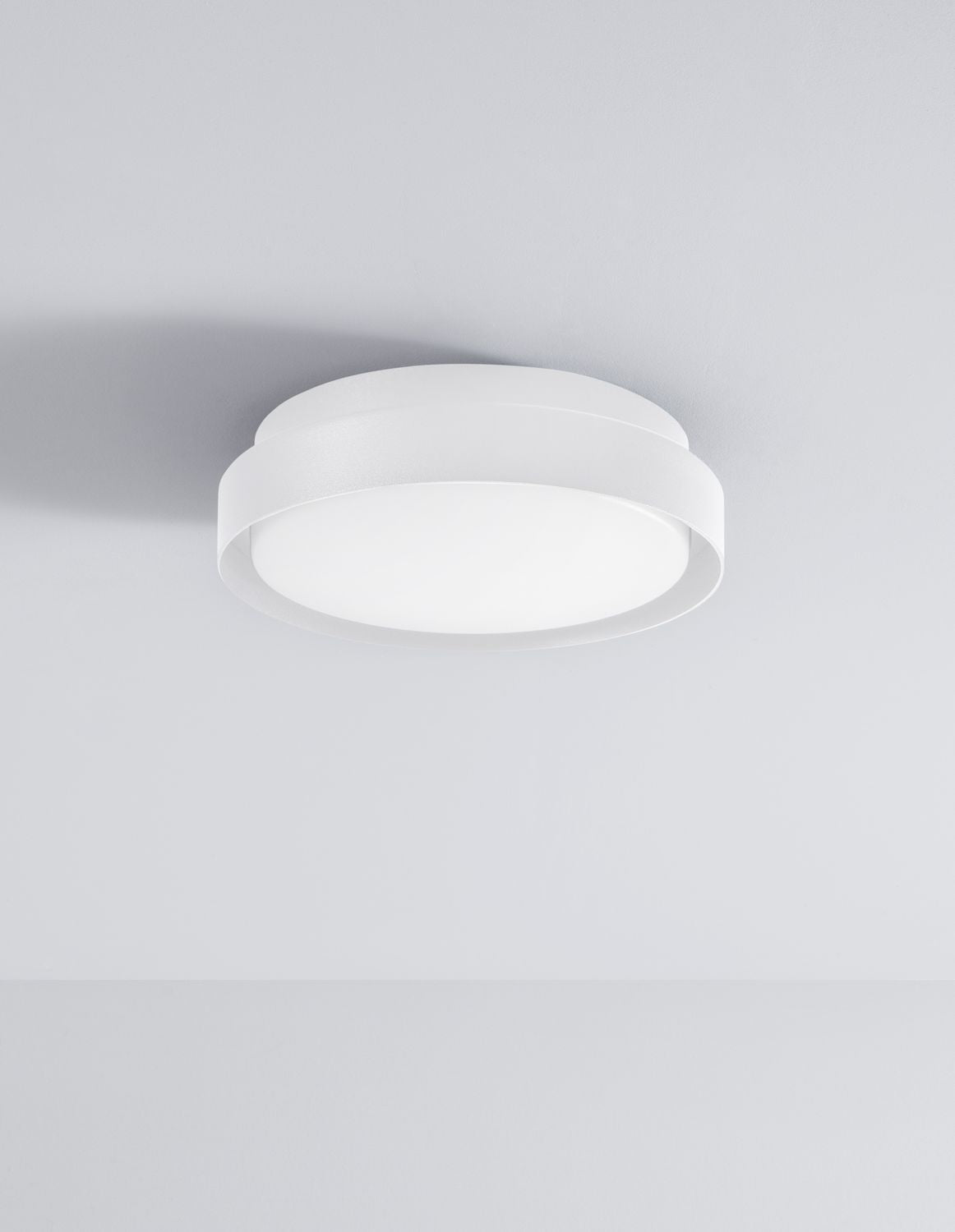 Plafonnier blanc éteint fixé au plafond, anneau métallique et vasque opaline