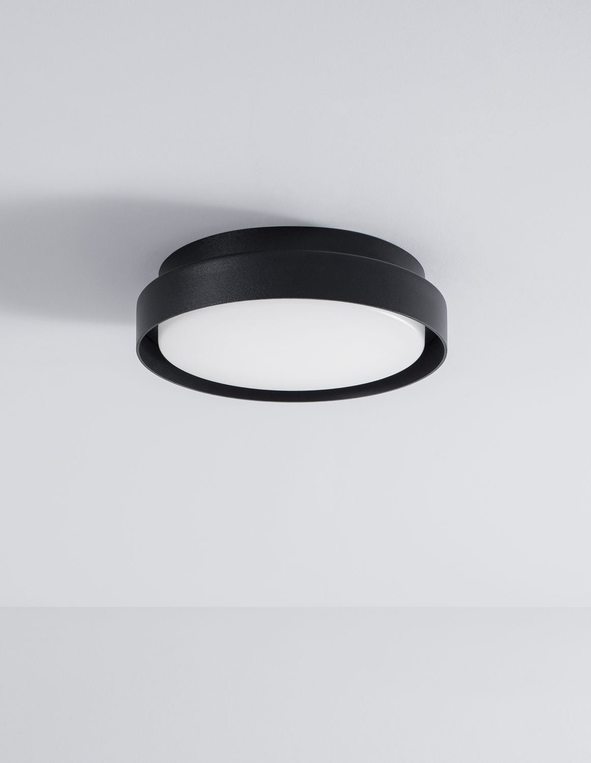 Le luminaire noir fixé au plafond blanc, éteint, photographié de dessous