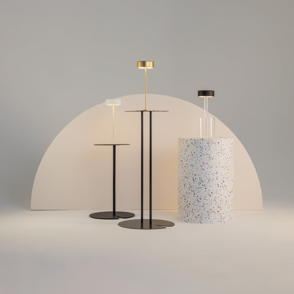 Mise en ambiance avec trois lampes design, la dorée au centre sur support noir.