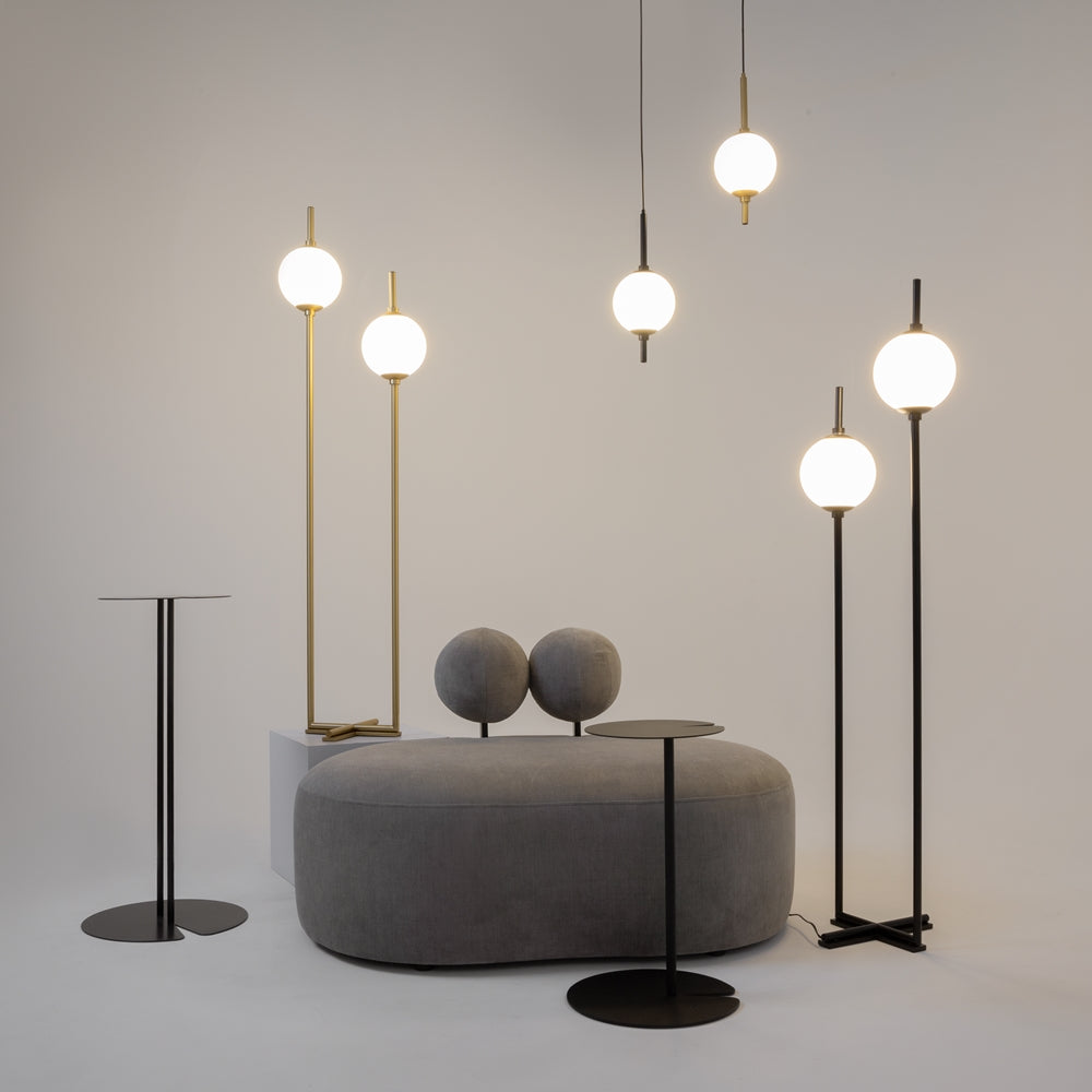 Mise en ambiance avec plusieurs luminaires, pouf rond et tables noires