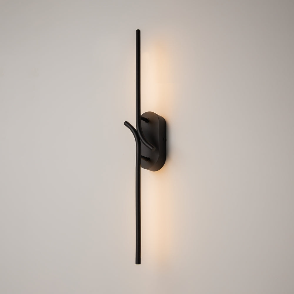 Applique murale noire allumée sur mur clair, halo lumineux chaud