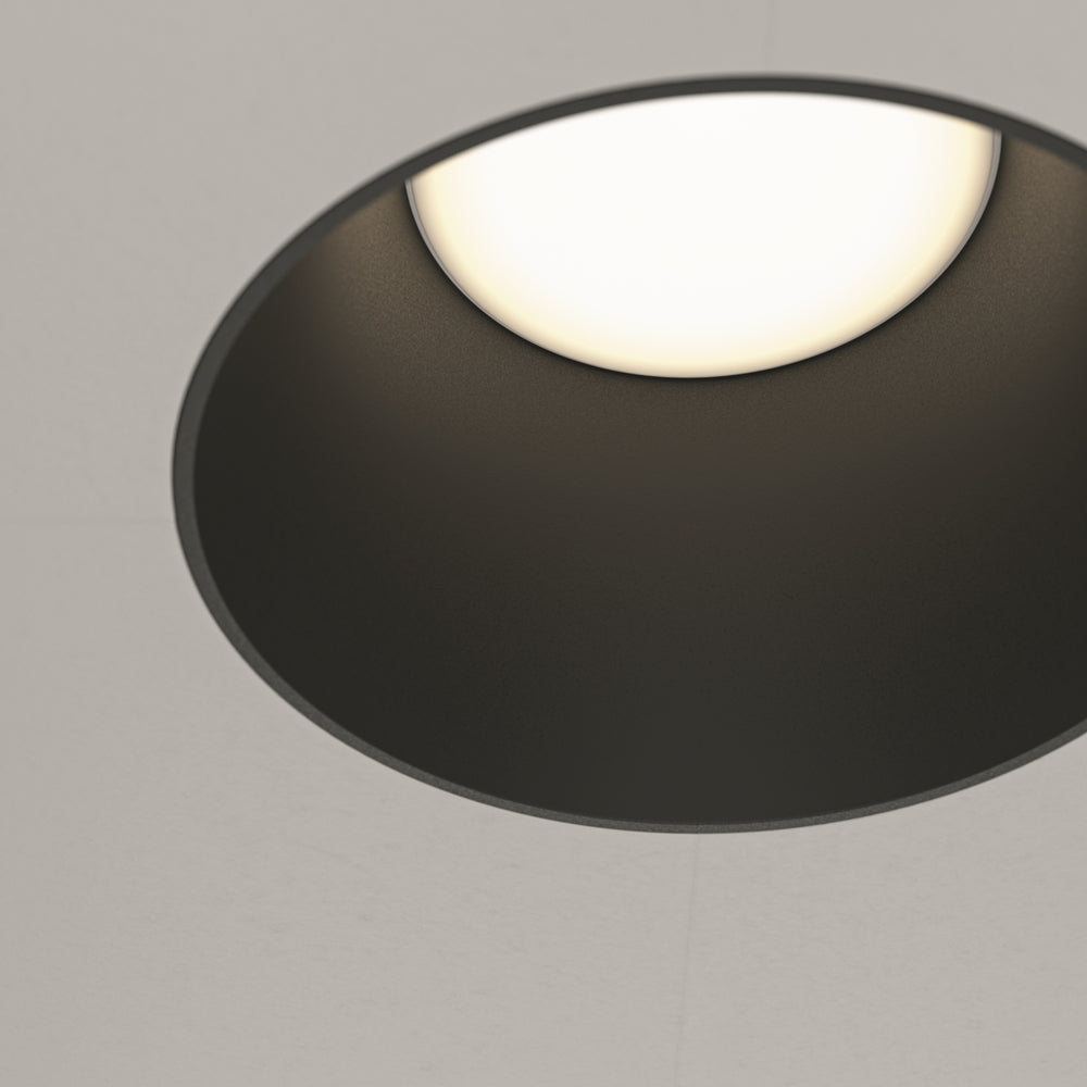Détail rapproché de l'ovale noir laqué vu en contre-plongée sur fond gris.