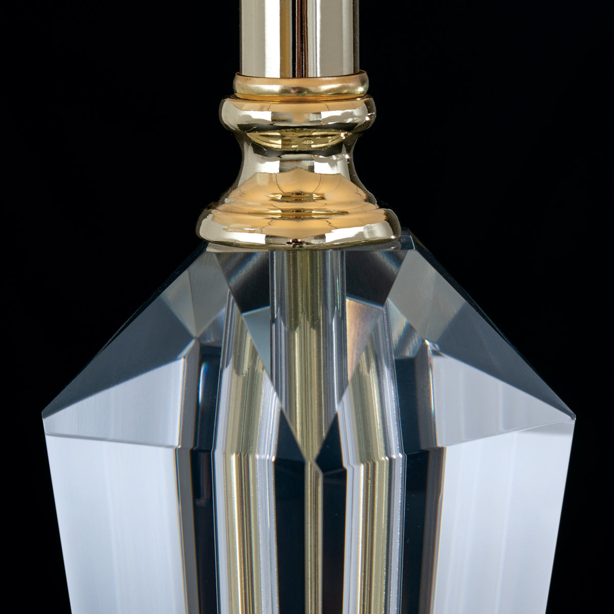 Gros plan du fût en cristal taillé et de la bague dorée sous la douille
