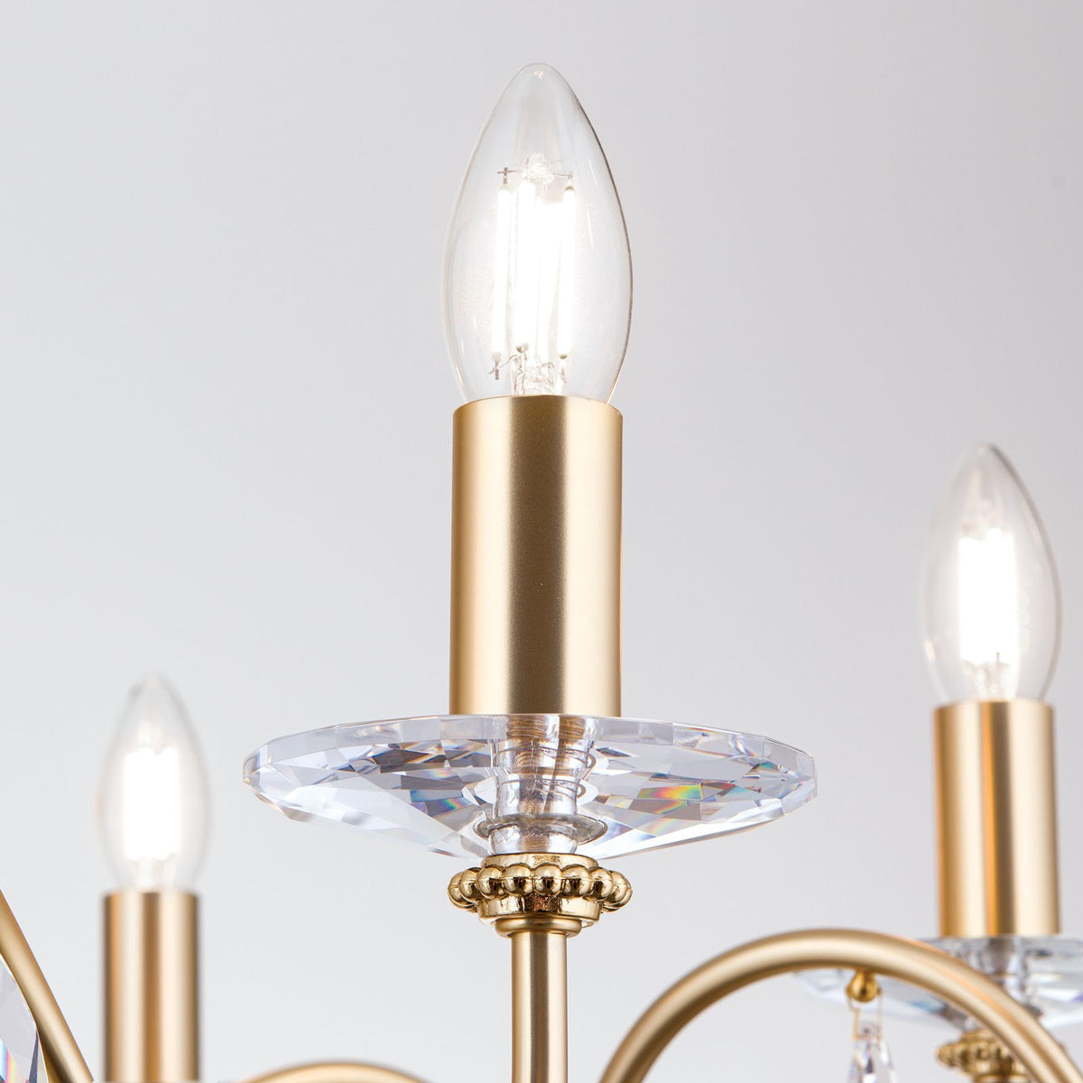 Détail d'une coupelle en verre taillé et douille dorée avec ampoule allumée