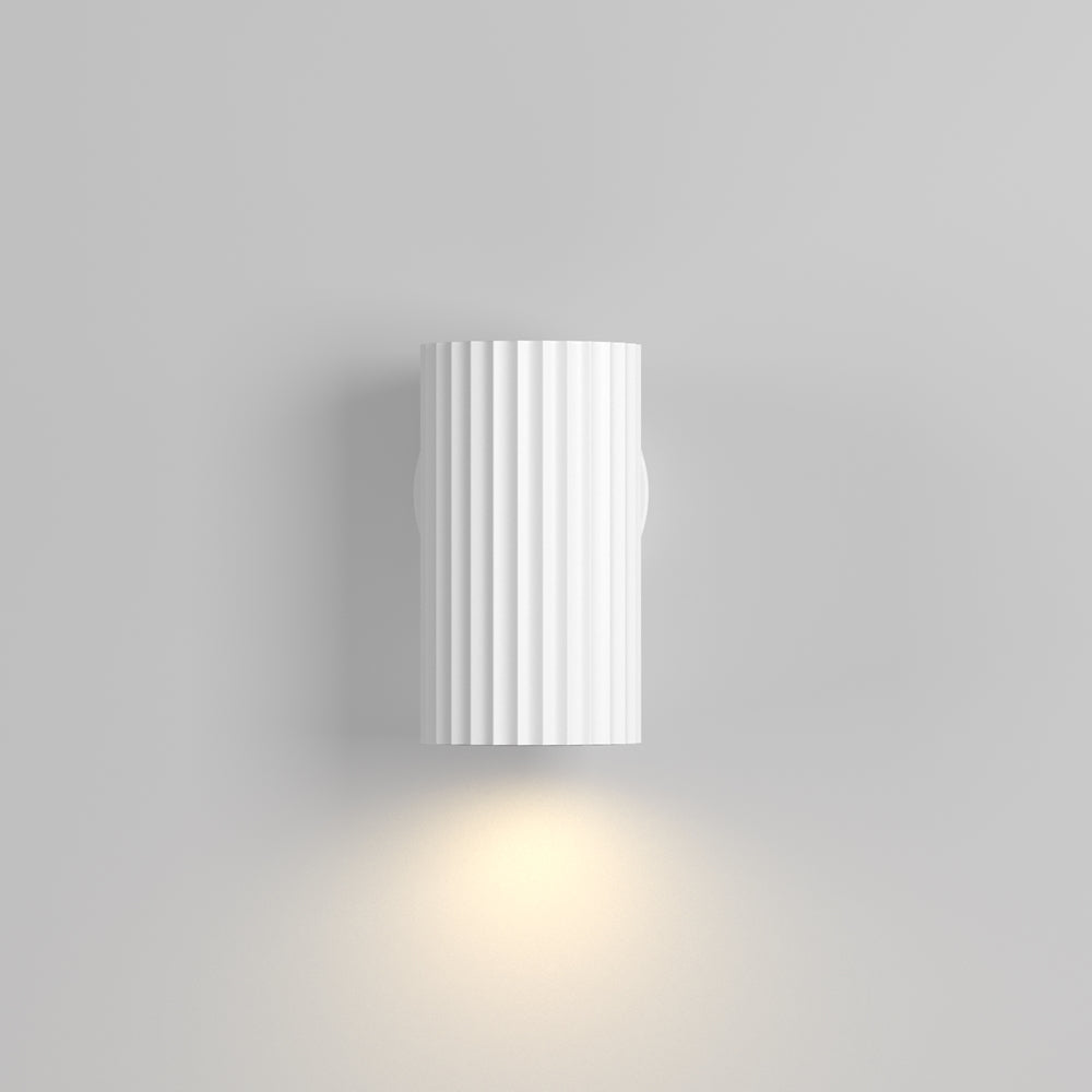 Mise en ambiance d'une applique blanche diffusant un halo chaud sur le mur