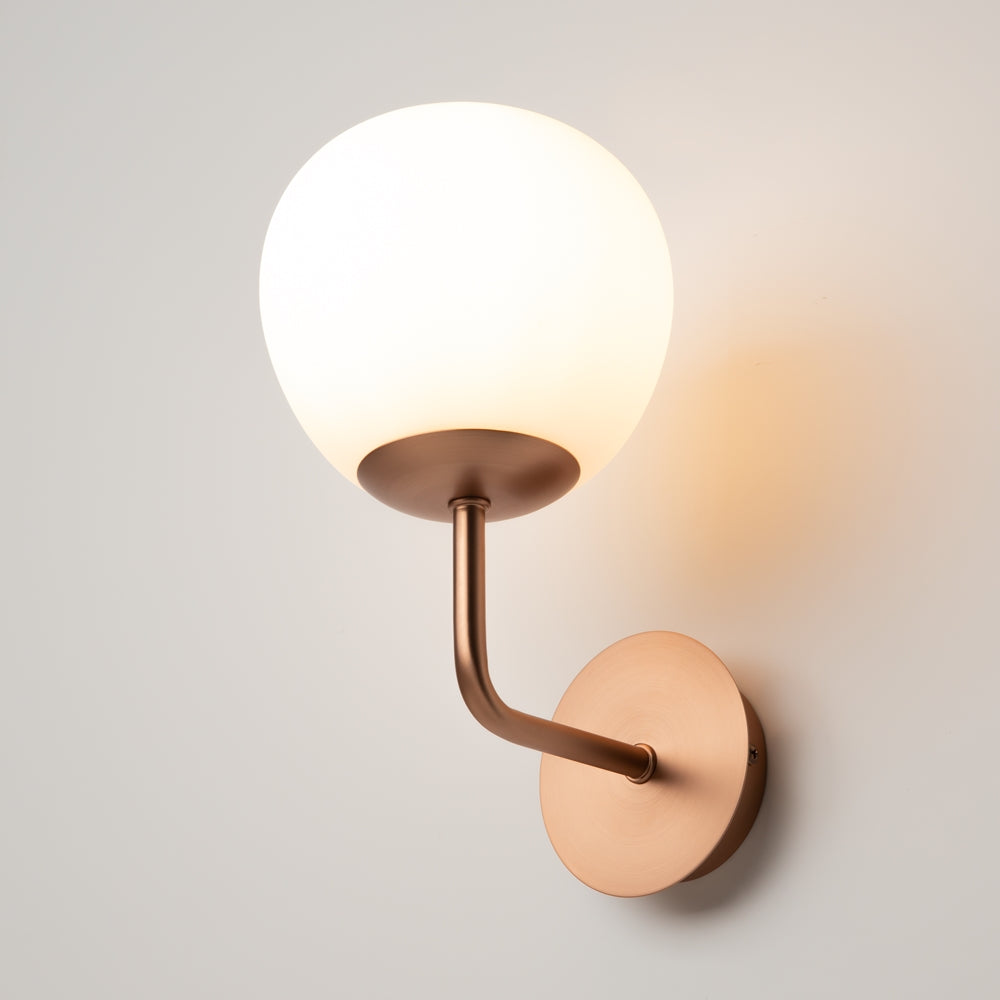 Applique allumée contre un mur clair, diffusant une lumière chaude et douce