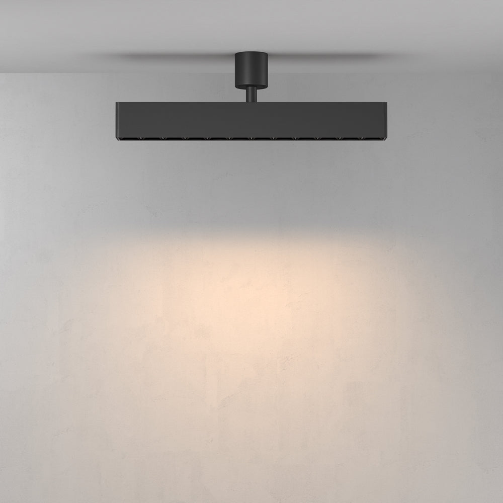 Vue de face du luminaire éclairant un mur clair dans une pièce sobre