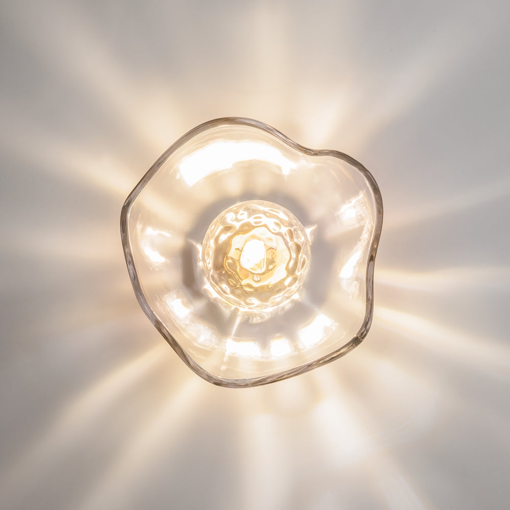 Vue frontale de l'applique allumée, lumière chaude diffusée en étoile.