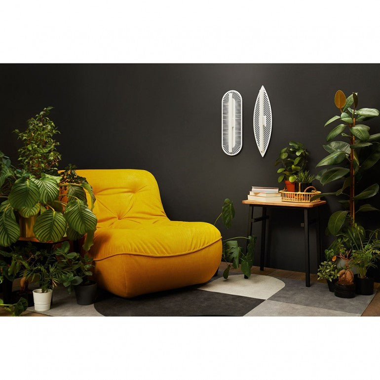 Mise en ambiance : fauteuil jaune, mur sombre, deux appliques murales allumées