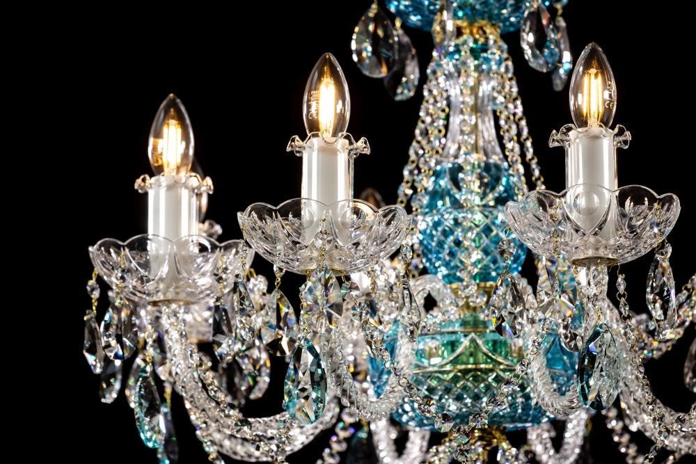 Détail des bras courbes, douilles bougies blanches et coupelles ajourées en cristal taillé.