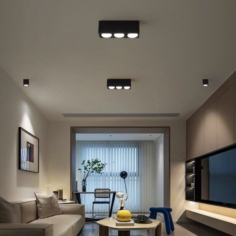 Vue d'intérieur avec plafonnier noir rectangulaire à trois diffuseurs fixé au plafond.