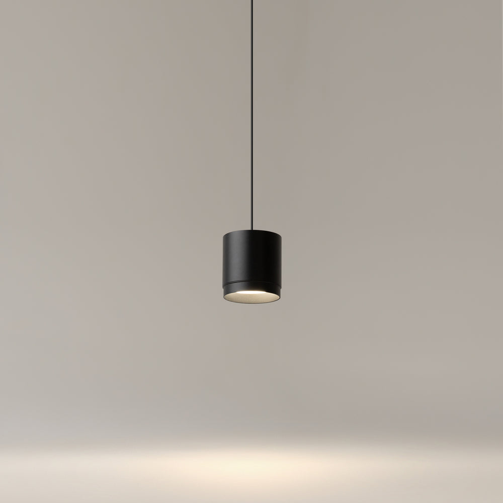 Même luminaire suspendu et allumé devant un mur gris clair uni