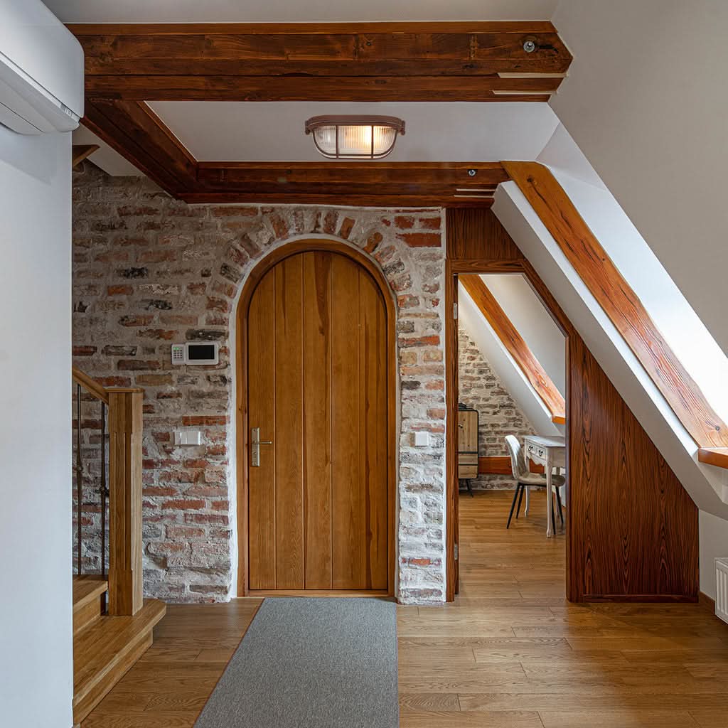 Mise en ambiance dans un couloir rustique, plafonnier fixé entre poutres et briques.