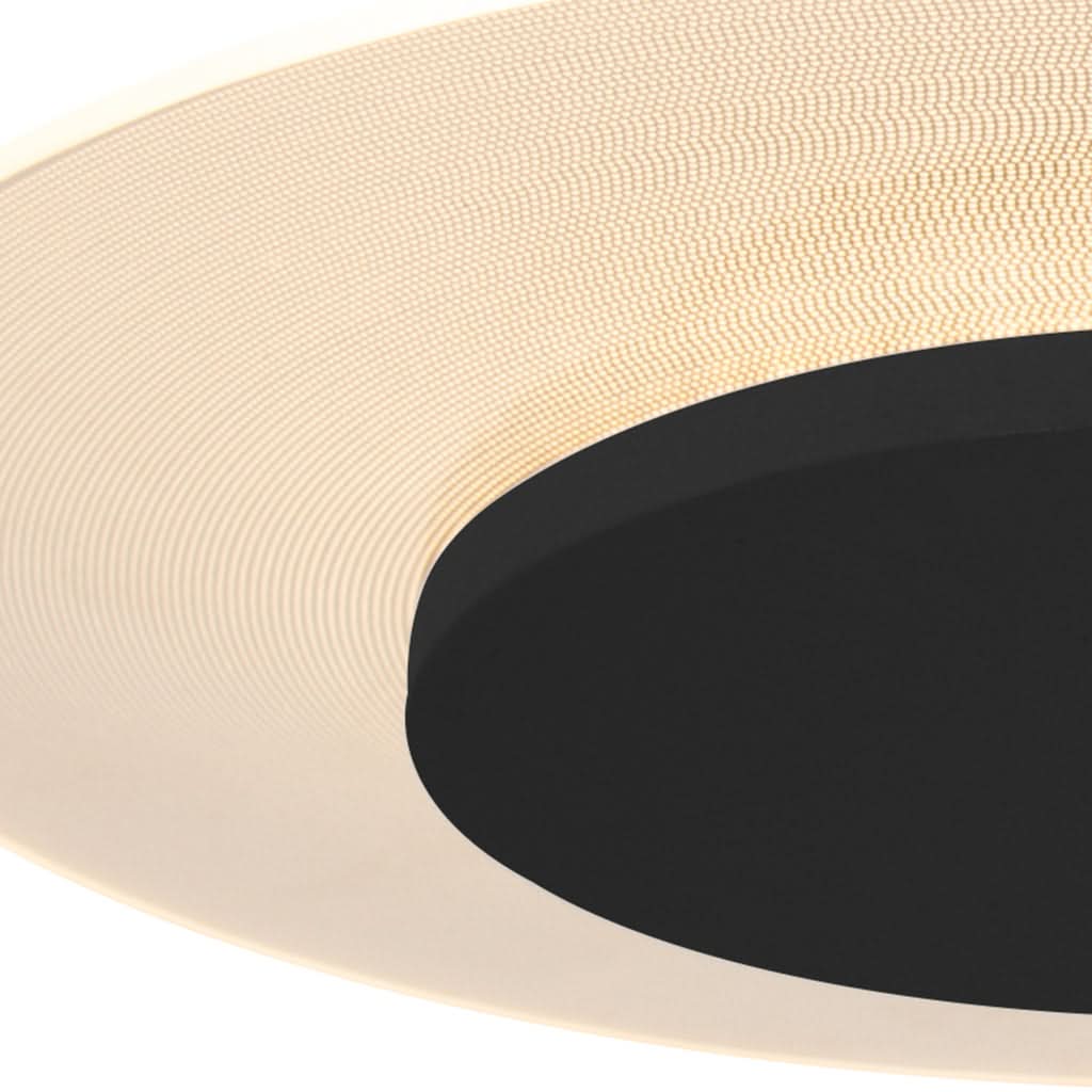 Gros plan sur la surface perforée claire et le disque noir du plafonnier.