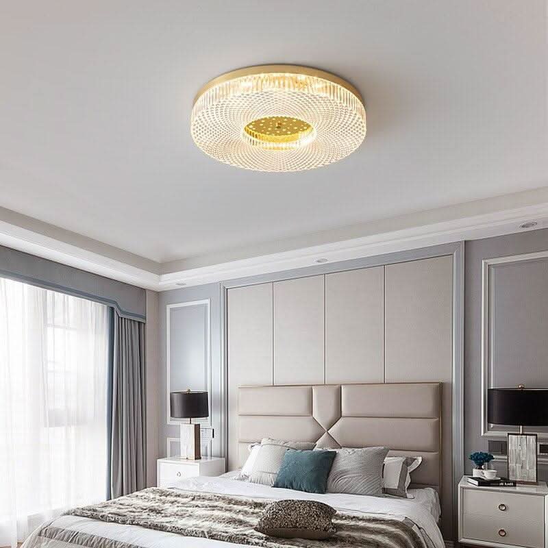Plafonnier doré dans une chambre à tête de lit capitonnée beige