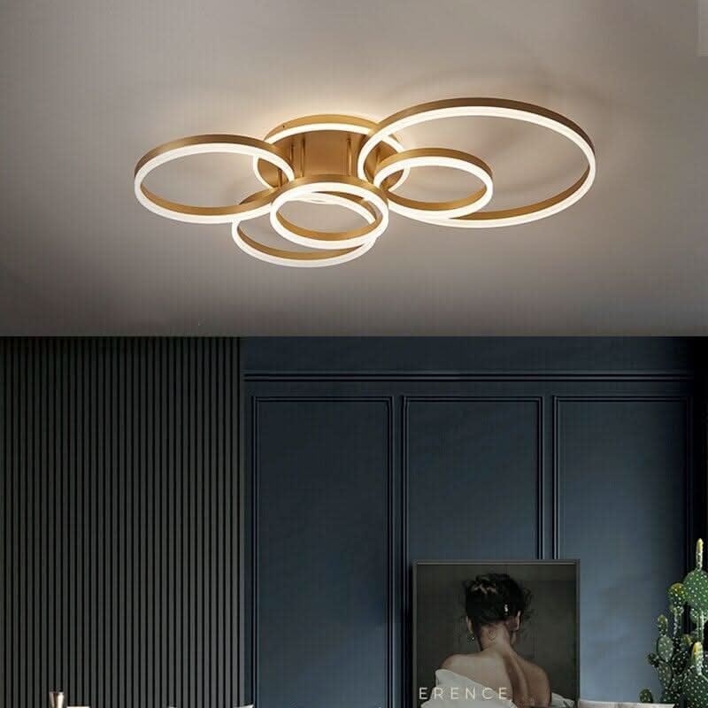 Plafonnier doré aux anneaux entrelacés vu de face, plafond blanc et mur sombre