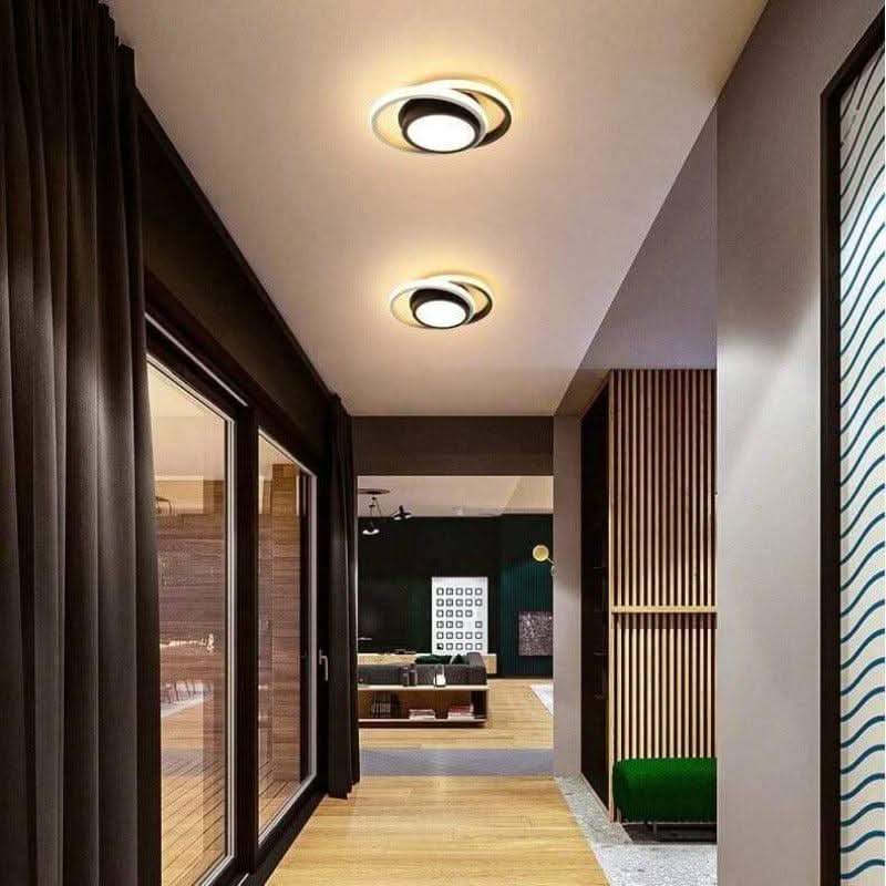 Vue en enfilade de deux plafonniers ronds noirs et blancs sur un plafond de couloir