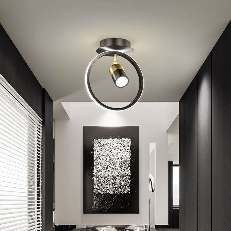Plafonnier rond noir et doré à spot orientable éclairant un tableau abstrait