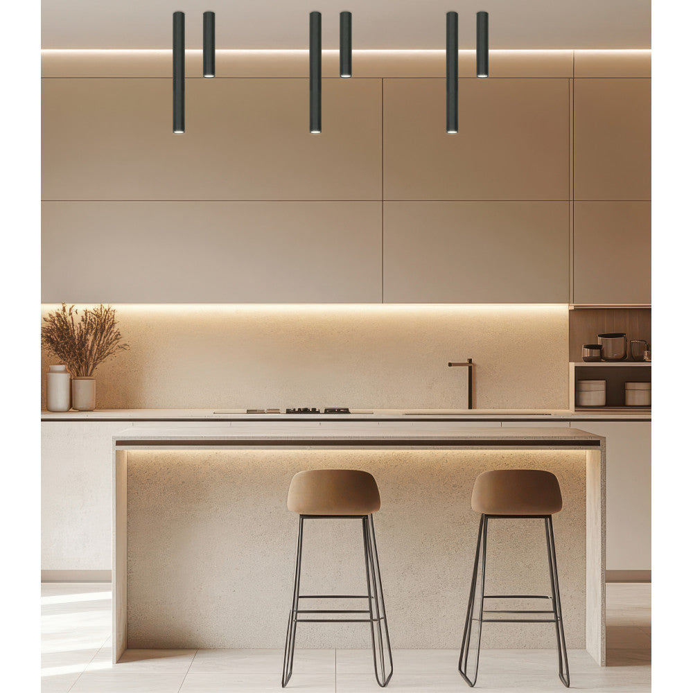Six plafonniers cylindriques noirs suspendus au-dessus d'un îlot de cuisine beige.