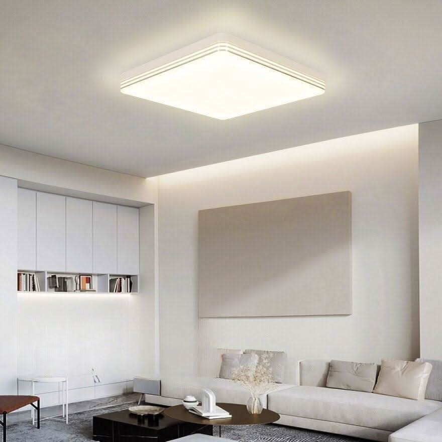 Ambiance intérieure claire, plafonnier carré au-dessus d'un canapé beige et d'un tableau
