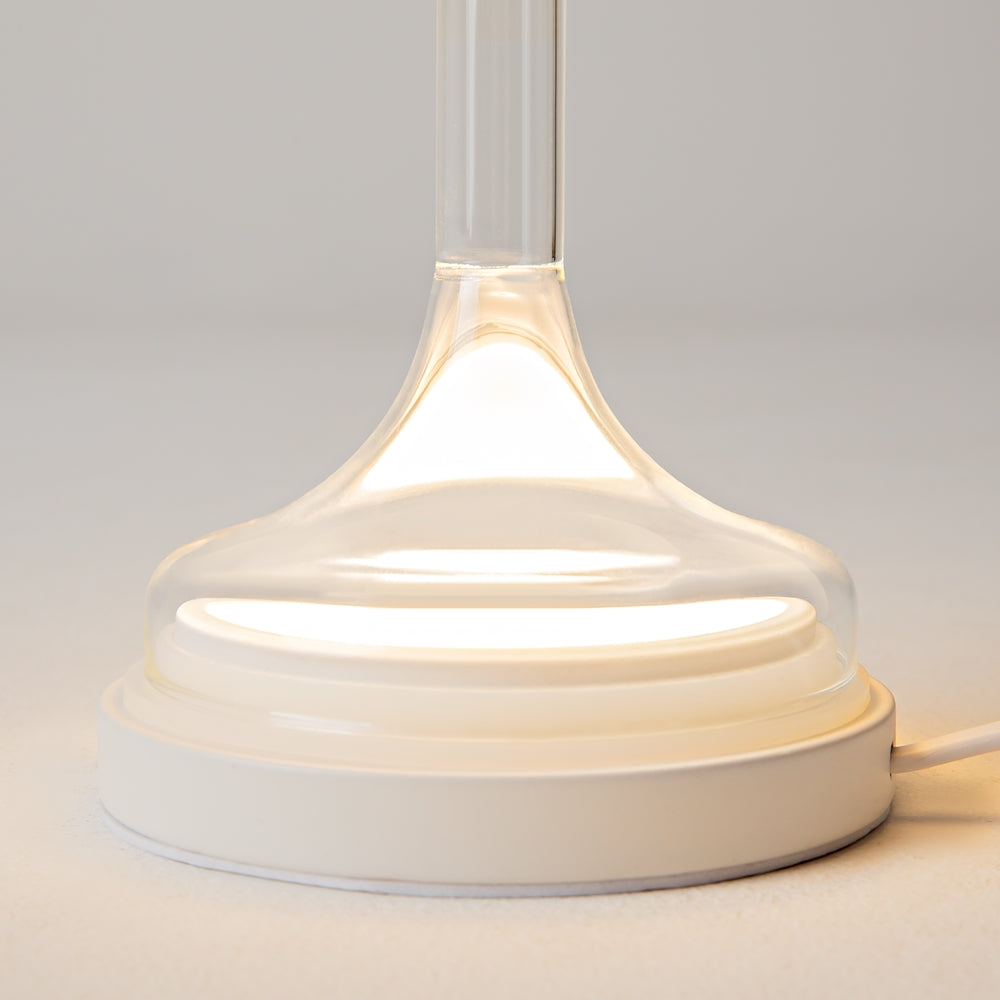 Détail de la base blanche et du pied en verre éclairé par le bas