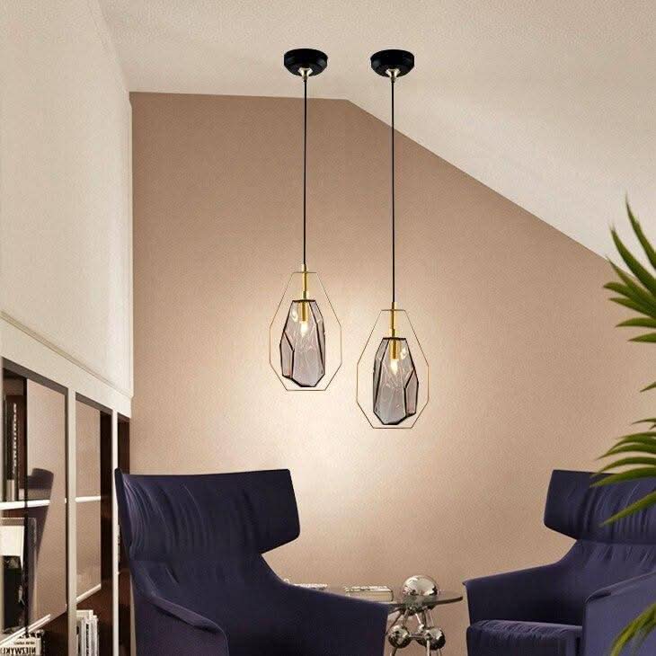 Deux suspensions en verre fumé dans un salon, près de fauteuils bleus