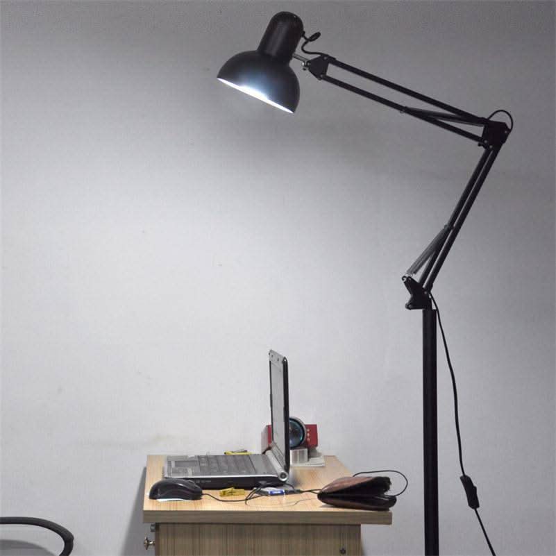 Mise en ambiance bureau : le lampadaire éclaire un ordinateur portable posé sur une table en bois.