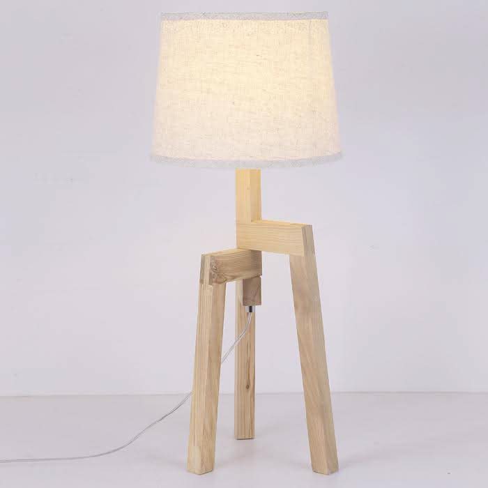 Gros plan sur petit lampadaire en bambou, abat-jour texturé, câble blanc au sol.
