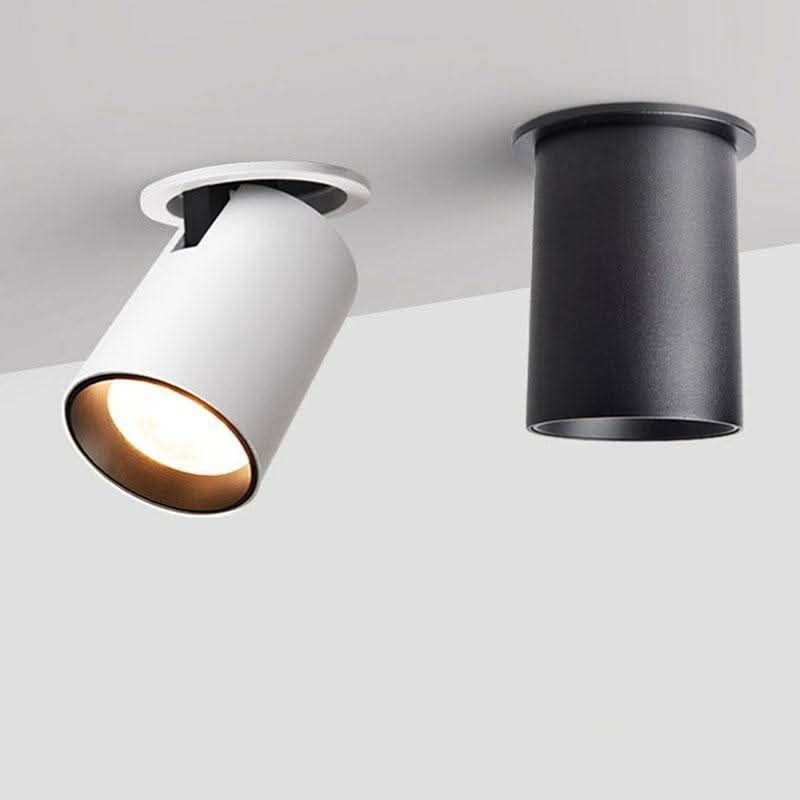 Deux spots cylindriques orientables, un blanc incliné et un noir droit, sur plafond.