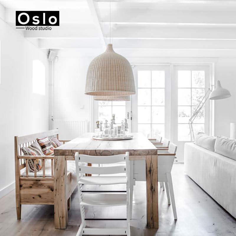 Suspension en rotin naturel installée au-dessus d'une table dans un intérieur blanc lumineux.
