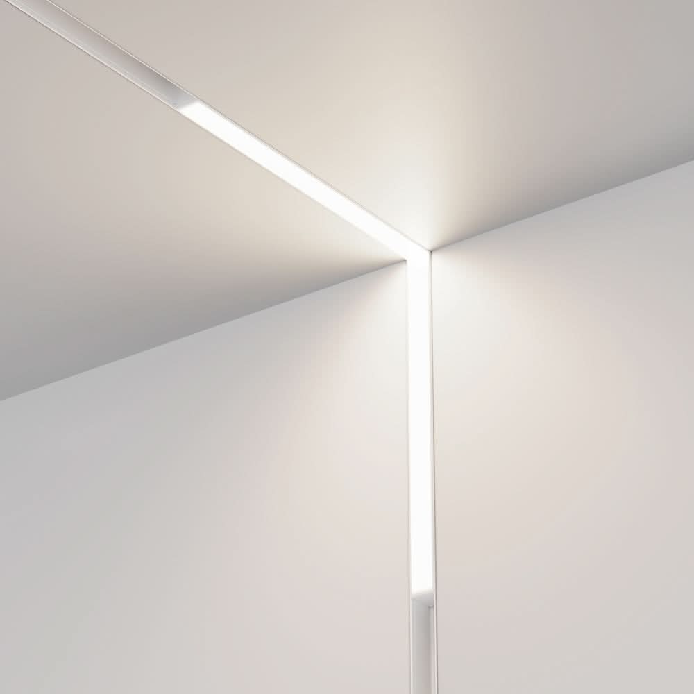 Luminaire linéaire encastré suivant l'angle entre plafond et mur, lumière allumée.