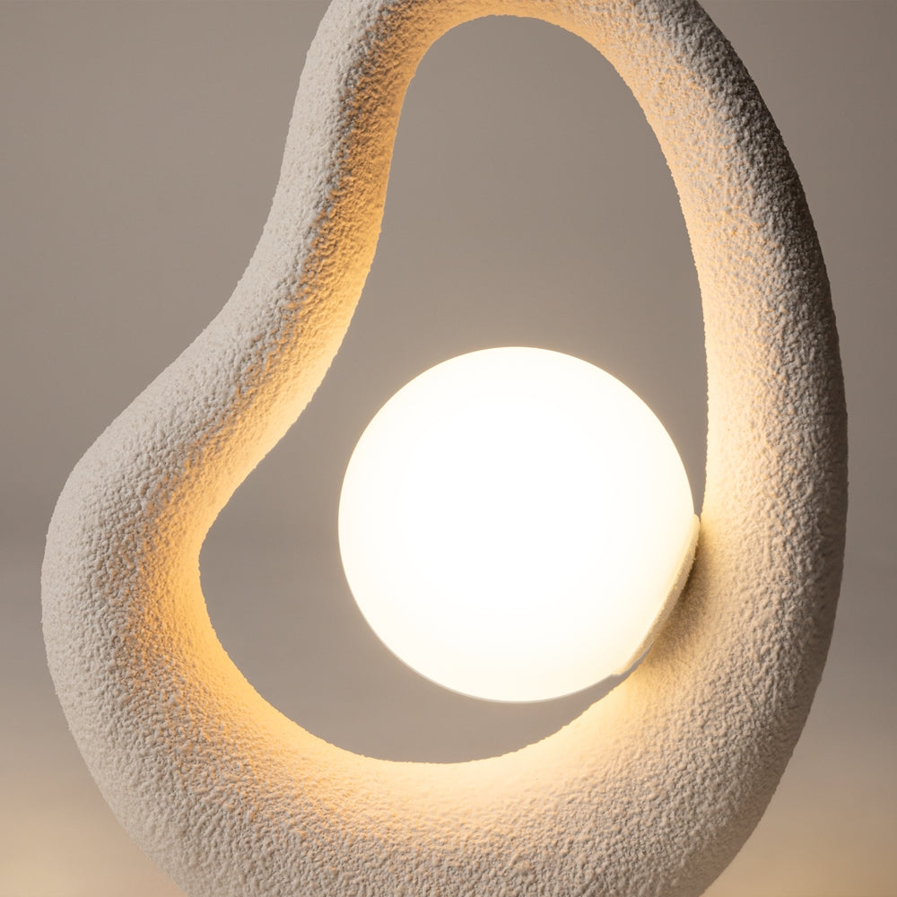 Gros plan sur la texture granuleuse blanche et la sphère lumineuse centrale allumée.