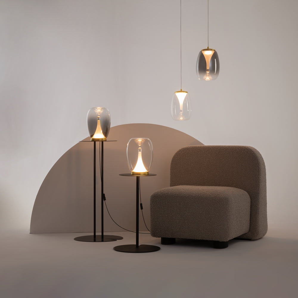 Mise en ambiance avec plusieurs luminaires dorés suspendus près d'un fauteuil.