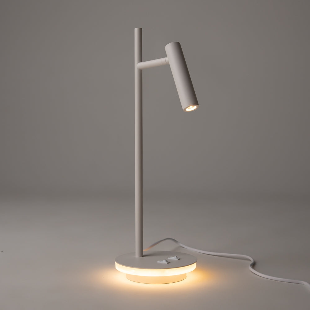 Lampe allumée dans une pièce sombre, halo lumineux diffusé par la base