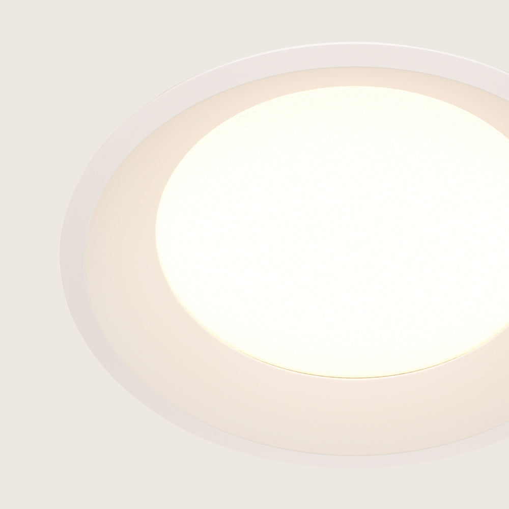 Gros plan du hublot lumineux et de la collerette blanche du spot.
