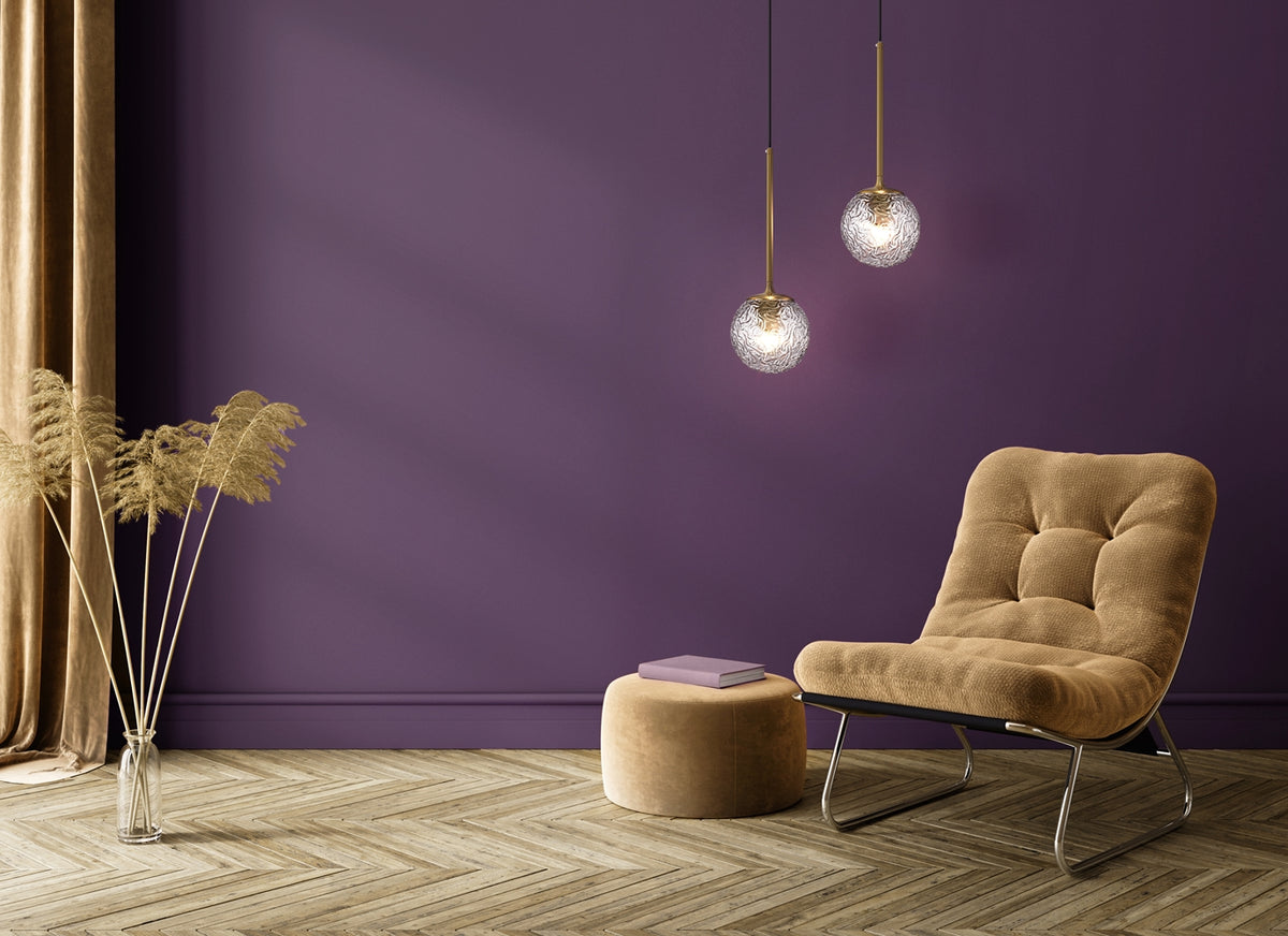 Mise en ambiance dans un intérieur violet avec deux suspensions allumées au-dessus d'un fauteuil
