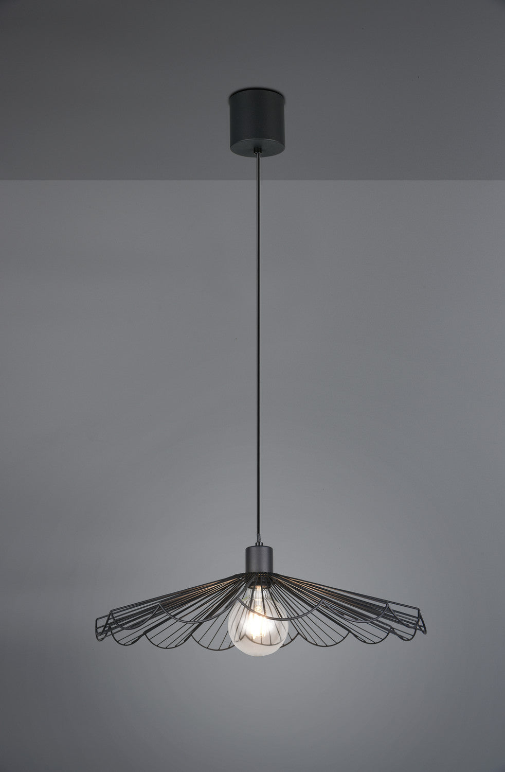 Mise en ambiance sombre : suspension noire allumée, ombres portées sur mur gris